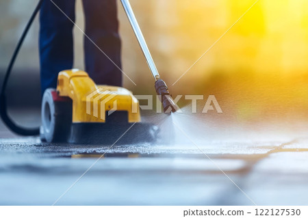 Worker is cleaning a concrete driveway with a pressure washer. generative ai 122127530