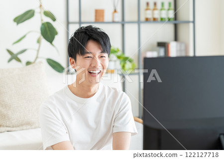 Young man watching tv in the living room Young man watching tv in the living room 122127718