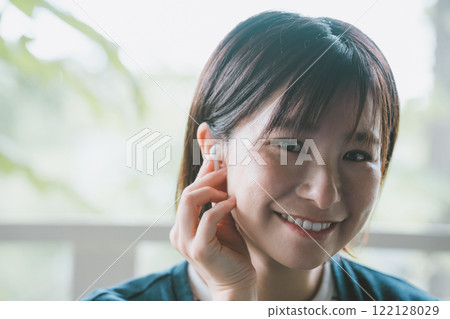 Woman using wireless earphones Woman using wireless earphones 122128029