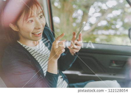 A woman in the passenger seat searches for a route using a smartphone map app A woman in the passenger seat searches for a route using a smartphone map app 122128054