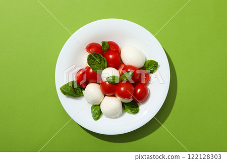 Caprese salad in a white bowl on a green background Caprese salad in a white bowl on a green background 122128303