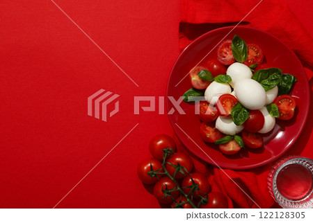 Caprese salad in a red bowl on a red background 122128305