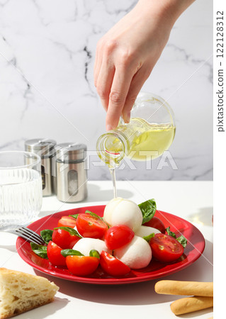 Caprese salad in a red bowl on a light background 122128312