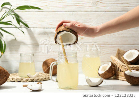 Coconut milk in a jar on a light background, with coconut fruits. Coconut milk in a jar on a light background, with coconut fruits. 122128323