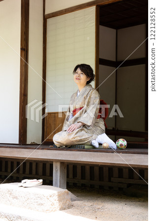 一個女人坐在門廊上,姿勢微微傾斜 一個女人坐在門廊上,姿勢微微傾斜 122128552