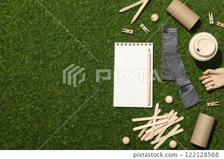 Materials for upcycling, wooden hand and notepad on green background, space for text 122128568