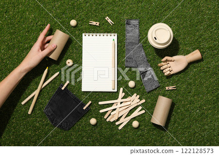 Materials for upcycling, hand and notepad on green background, top view Materials for upcycling, hand and notepad on green background, top view 122128573