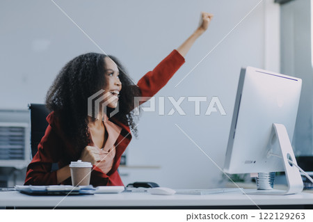 Excited african American woman sit at desk feel euphoric win online lottery, happy black woman overjoyed get mail at laptop being promoted at work, biracial girl amazed read good news at computer 122129263