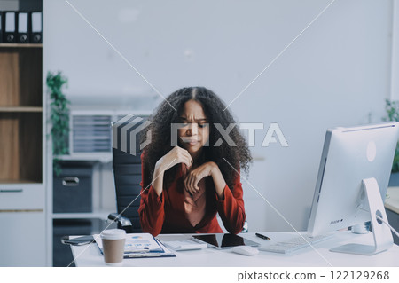 Stressed business woman sitting at office workplace looking at laptop computer. Tired and overworked businesswoman. Young exhausted student girl in stress. Stressed business woman sitting at office workplace looking at laptop computer. Tired and overworked businesswoman. Young exhausted student girl in stress. 122129268
