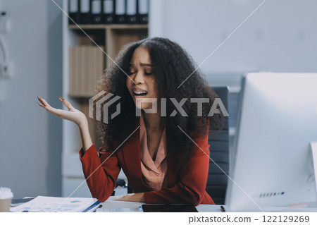Stressed business woman sitting at office workplace looking at laptop computer. Tired and overworked businesswoman. Young exhausted student girl in stress. 122129269