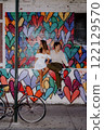 A couple poses by a colorful heart mural in the city, happily enjoying each other 122129570