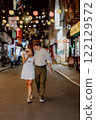 A couple strolls through a romantic urban night, enjoying a lively atmosphere and charm 122129572
