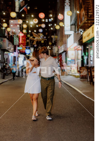 A couple strolls through a romantic urban night, enjoying a lively atmosphere and charm 122129572