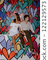 A couple poses by a colorful heart mural in the city, happily enjoying each other 122129573