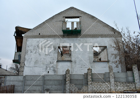 Abandoned brick house with deteriorated facade and broken windows in urban setting 122130358