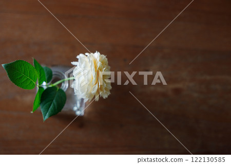 Closeup of Yellow beautiful blooming rose in glass vase on wooden table. Closeup of Yellow beautiful blooming rose in glass vase on wooden table. 122130585