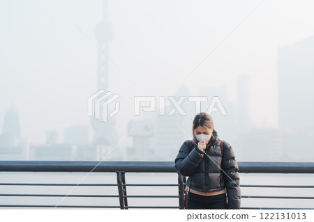 young Asian woman wearing respiratory mask protect and filter pm or particulate matter against bad Air Pollution in Shanghai City, China. Air Quality Index, AQI, Unhealthy, healthcare concept 122131013