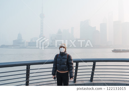young Asian woman wearing respiratory mask protect and filter pm or particulate matter against bad Air Pollution in Shanghai City, China. Air Quality Index, AQI, Unhealthy, healthcare concept 122131015