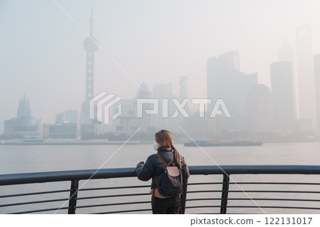 young Asian woman wearing respiratory mask protect and filter pm or particulate matter against bad Air Pollution in Shanghai City, China. Air Quality Index, AQI, Unhealthy, healthcare concept 122131017