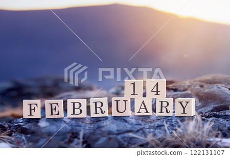 February 14 is the date of the Valentine's Day holiday made of wooden cubes on the background of blue mountains at sunset or sunrise. Valentines Day Celebration takes place on the widely recognized February 14 is the date of the Valentine's Day holiday made of wooden cubes on the background of blue mountains at sunset or sunrise. Valentines Day Celebration takes place on the widely recognized 122131107