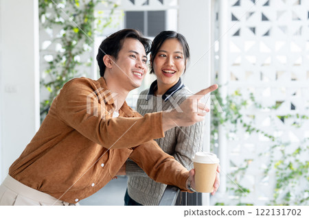 A lovely couple enjoys a conversation and gazes at the view on the balcony during a coffee break. A lovely couple enjoys a conversation and gazes at the view on the balcony during a coffee break. 122131702