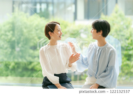 Businesswomen sitting by the window and talking 122132537