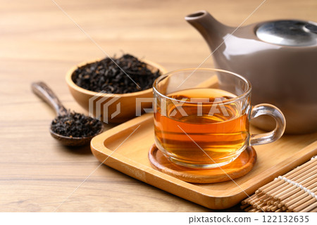 Black tea in cup glass with dried tea leaves, Healthy herbal drink 122132635