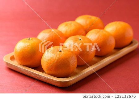 Mandarin tangerine orange fruit on wooden plate with red background, Lucky food in Lunar New Year 122132670