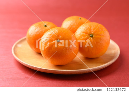 Mandarin tangerine orange fruit on wooden plate with red background, Lucky food in Lunar New Year 122132672