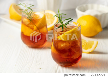 Iced tea or alcoholic cocktail with ice, rosemary and lemon slices on the white table. Iced tea or alcoholic cocktail with ice, rosemary and lemon slices on the white table. 122132721