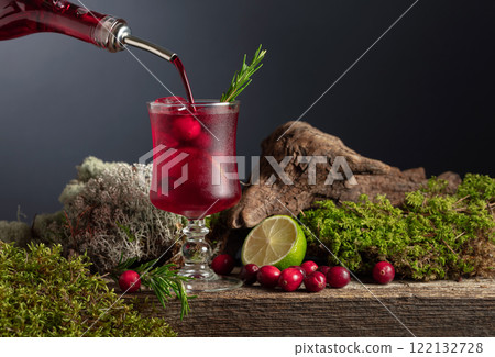 Cranberry cocktail with ice, lime, and rosemary on a old wooden board. Cranberry cocktail with ice, lime, and rosemary on a old wooden board. 122132728