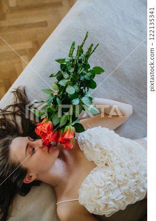 Sensual woman lying on bed smelling red rose. Concept of Valentine's Day, love and relationship Sensual woman lying on bed smelling red rose. Concept of Valentine's Day, love and relationship 122135341