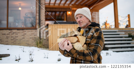 Close up of elderly man is chopping wood outside. He is preparing logs for the fireplace. 122135354