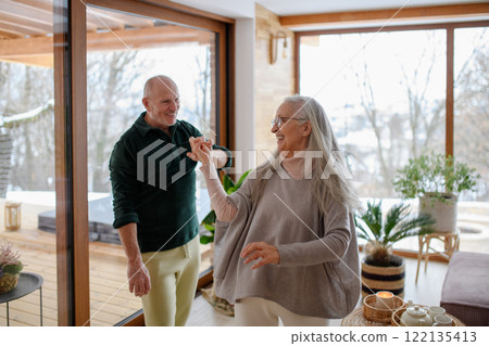 Older couple in love, having fun and dancing in living room. 122135413