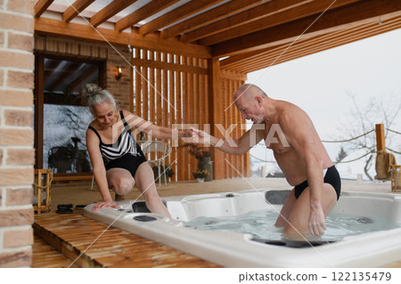 Senior couple enering a hot tub during Valentine's weekend with spa. 122135479