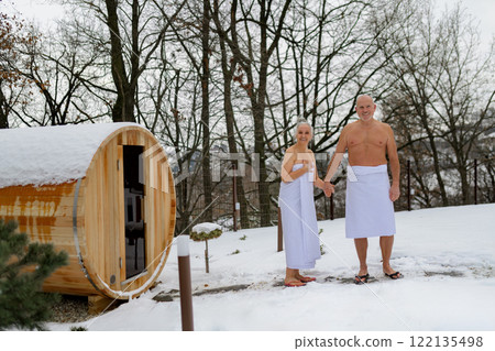 Elderly couple coming out of sauna after a sauna session. Winter spa weekend getaway for elderly people. 122135498