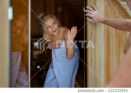 Senior couple using small sauna during cold winter day. Spa weekend getaway for elderly people. Senior couple using small sauna during cold winter day. Spa weekend getaway for elderly people. 122135501