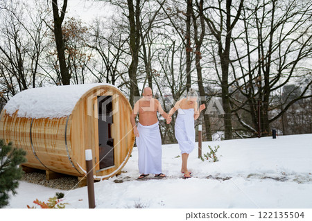 Elderly couple coming out of sauna after a sauna session. Winter spa weekend getaway for elderly people. 122135504