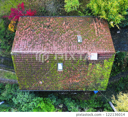 Drone capturing aerial view of damaged roof covered by moss 122136014