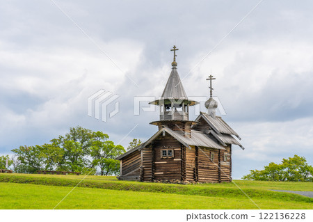 Traditional wooden church of kizhi pogost rising on verdant hill, surrounding karelian landscape beneath overcast sky Traditional wooden church of kizhi pogost rising on verdant hill, surrounding karelian landscape beneath overcast sky 122136228