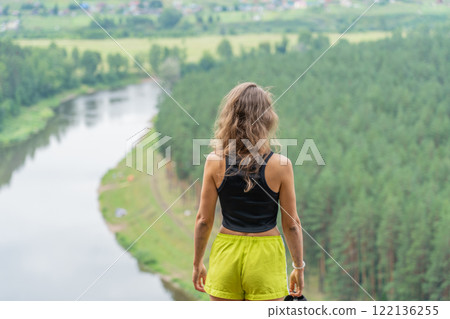Young sportswoman enjoying panoramic view of river and green forest during hiking trip in nature 122136255