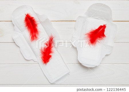 Women hygiene products or Sanitary pad with red feather on colored background. Pastel color. Closeup. Empty place for text. Female daily hygiene 122136445