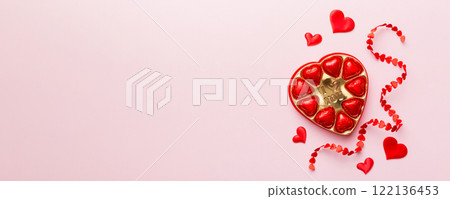 Delicious chocolate pralines in red box for Valentine's Day. Heart shaped box of chocolates top view with copy space 122136453