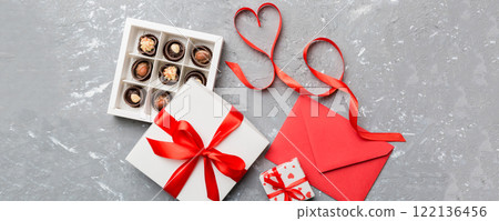 Envelope on colored background for Valentine Day with gift box and chocolate. Heart shaped with gift box of chocolates top view with copy space Envelope on colored background for Valentine Day with gift box and chocolate. Heart shaped with gift box of chocolates top view with copy space 122136456