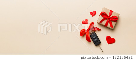 Black car key in a present box with a ribbon and red heart on colored background. Valentine day composition Top view Black car key in a present box with a ribbon and red heart on colored background. Valentine day composition Top view 122136481