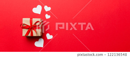 Valentine day composition: red gift box with bow and heart. Christmas present. View from above. Space for text. Holday greeting card Valentine day composition: red gift box with bow and heart. Christmas present. View from above. Space for text. Holday greeting card 122136548