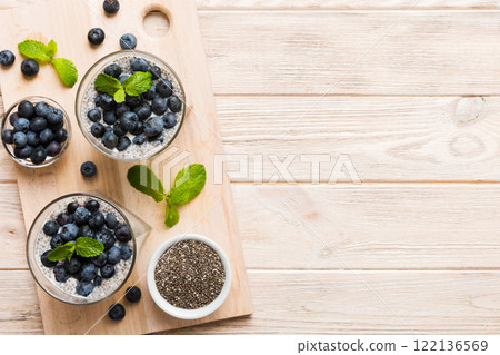 Healthy breakfast or morning with chia seeds vanilla pudding and blueberry berries on table background, vegetarian food, diet and health concept. Chia pudding with coconut milk and blueberry 122136569