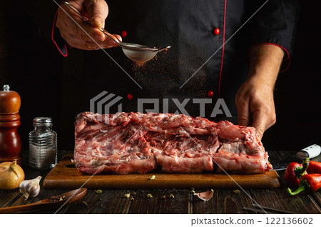 Expertly slicing and seasoning a large cut of meat, the chef enhances flavors with spices while surrounded by ingredients. The warm kitchen atmosphere invites culinary creativity Expertly slicing and seasoning a large cut of meat, the chef enhances flavors with spices while surrounded by ingredients. The warm kitchen atmosphere invites culinary creativity 122136602