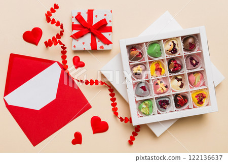 Red envelope with candy and gift box and Valentines hearts on colored background. Flat lay, top view. Romantic love letter for Holiday concept Red envelope with candy and gift box and Valentines hearts on colored background. Flat lay, top view. Romantic love letter for Holiday concept 122136637