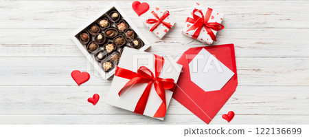 Envelope on colored background for Valentine Day with gift box and chocolate. Heart shaped with gift box of chocolates top view with copy space 122136699